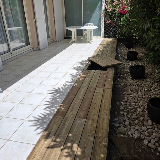 Même terrasse après travaux : platelage bois le long du carrelage, galets et pots noirs