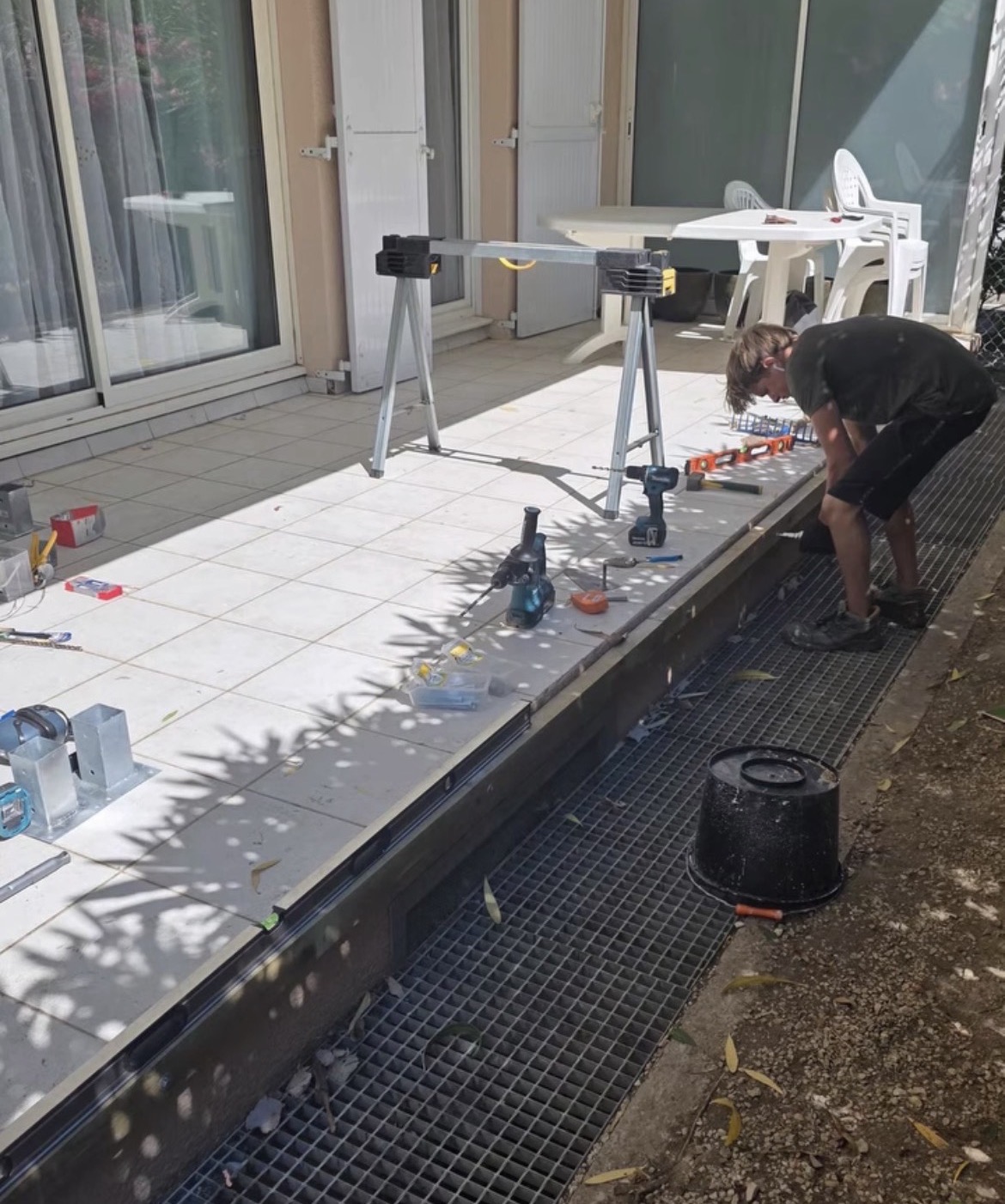 Terrasse carrelée pendant les travaux, caniveau à grille encore apparent